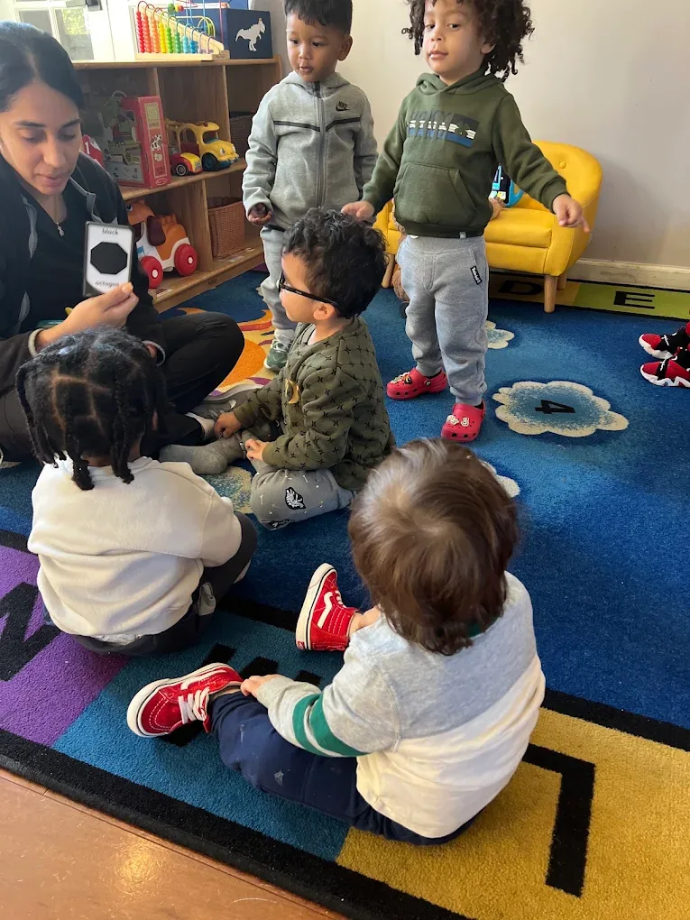 Teacher and toddlers playing together on the classroom rug